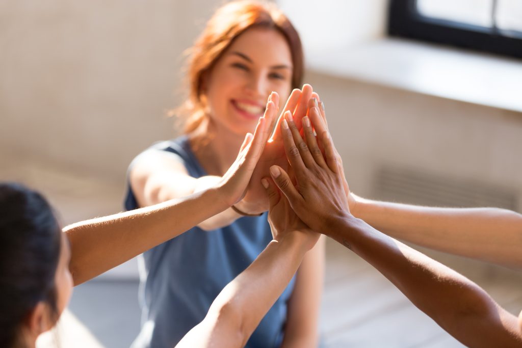 A group of smiling women enthusiastically high five each other, their hands meeting in mid-air