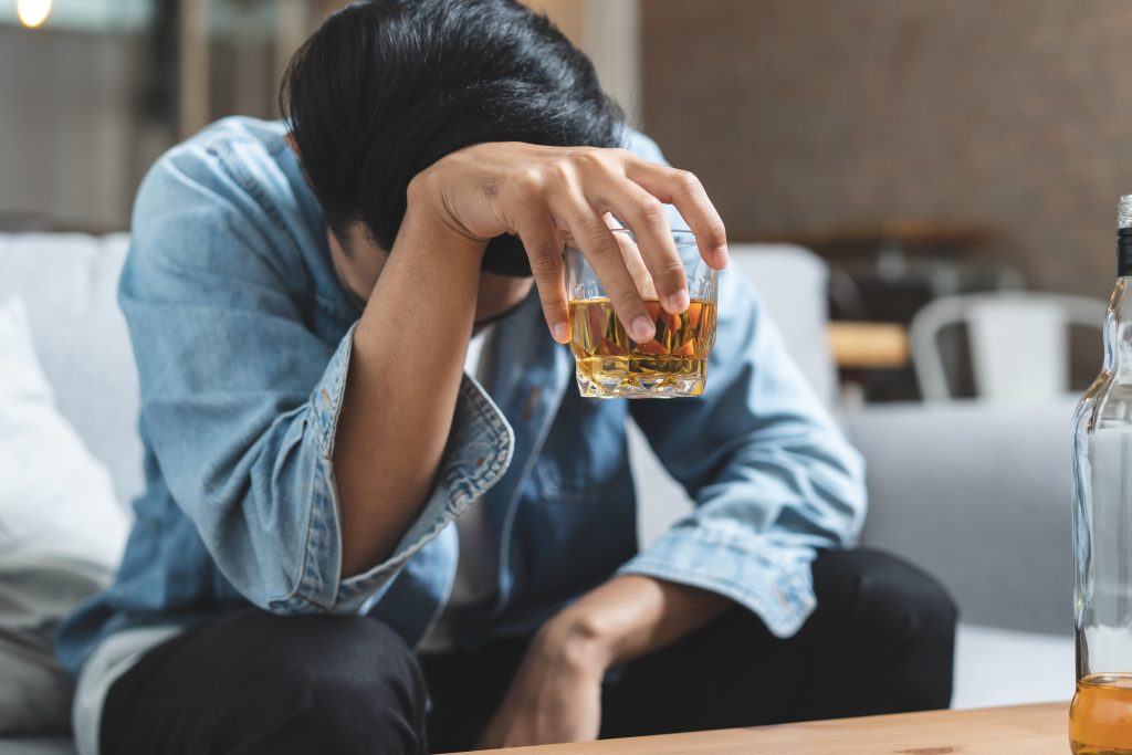 A melancholic man holds a glass of alcohol