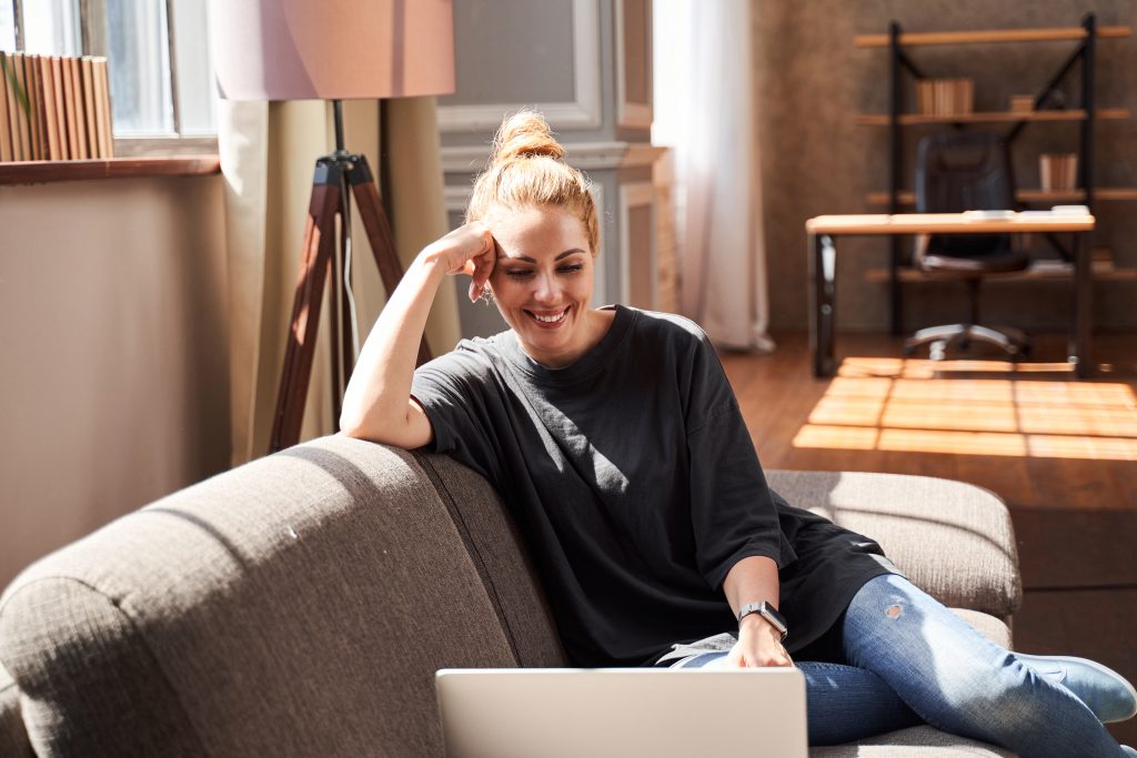 A woman wearing a smile while concentrating on her laptop