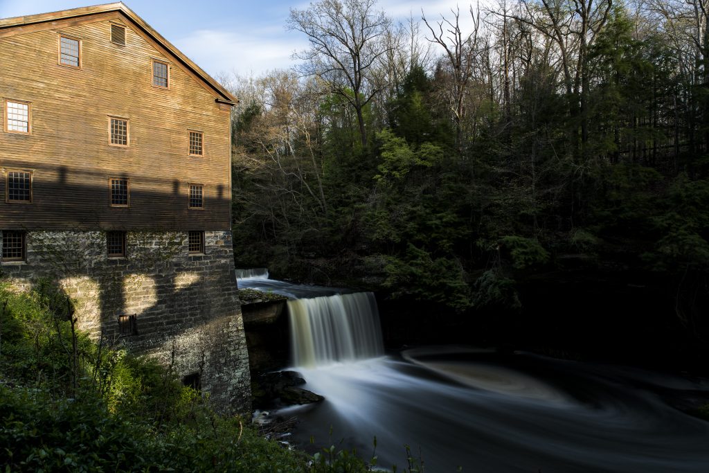 A grand building with a cascading waterfall in its foreground, complemented by the serene flow of water nearby