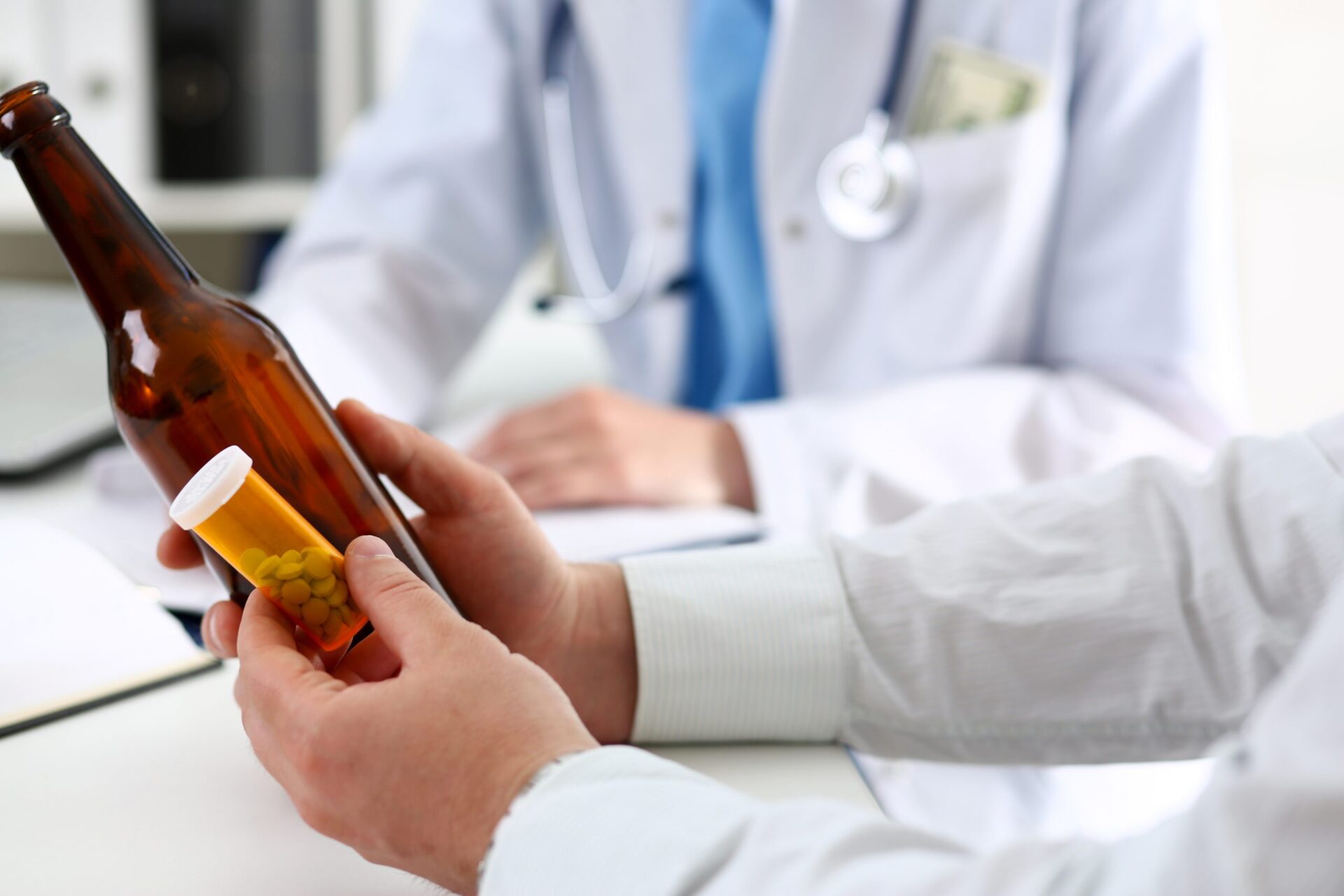 A doctor holding a bottle of pills and a bottle of beer