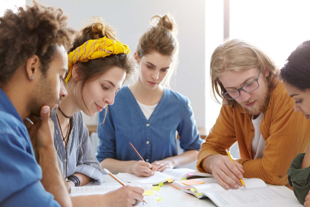 A group of individuals engaged in writing and studying together in a focused environment.